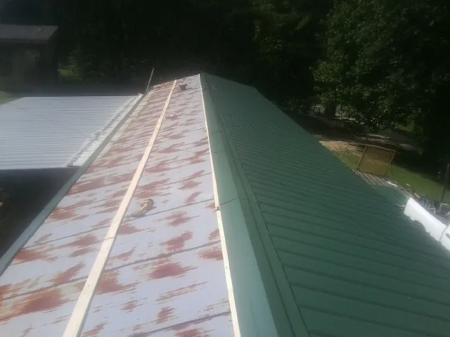 Old rusted panels beside newly installed green metal roofing — Wind Damage Roof Repair by Roofing Brothers in Portage Des Sioux