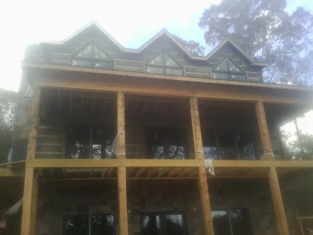 Dormers and porch framing on a large log home under construction — Roof Coating work by our crew in Portage Des Sioux