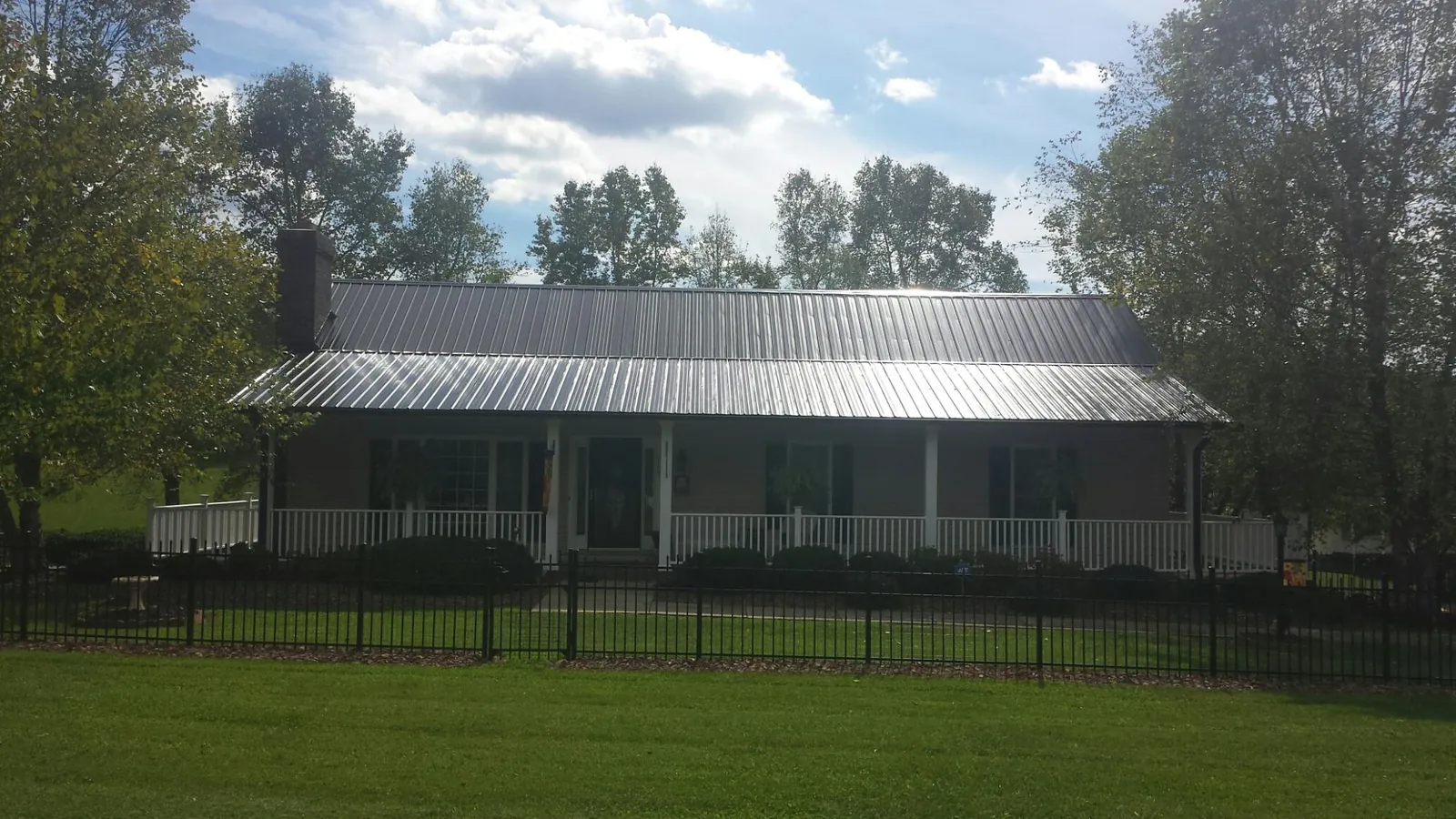 Gray metal roof on a brick ranch with a full width front porch — Gutter Guard Installation work by our crew in Portage Des Sioux