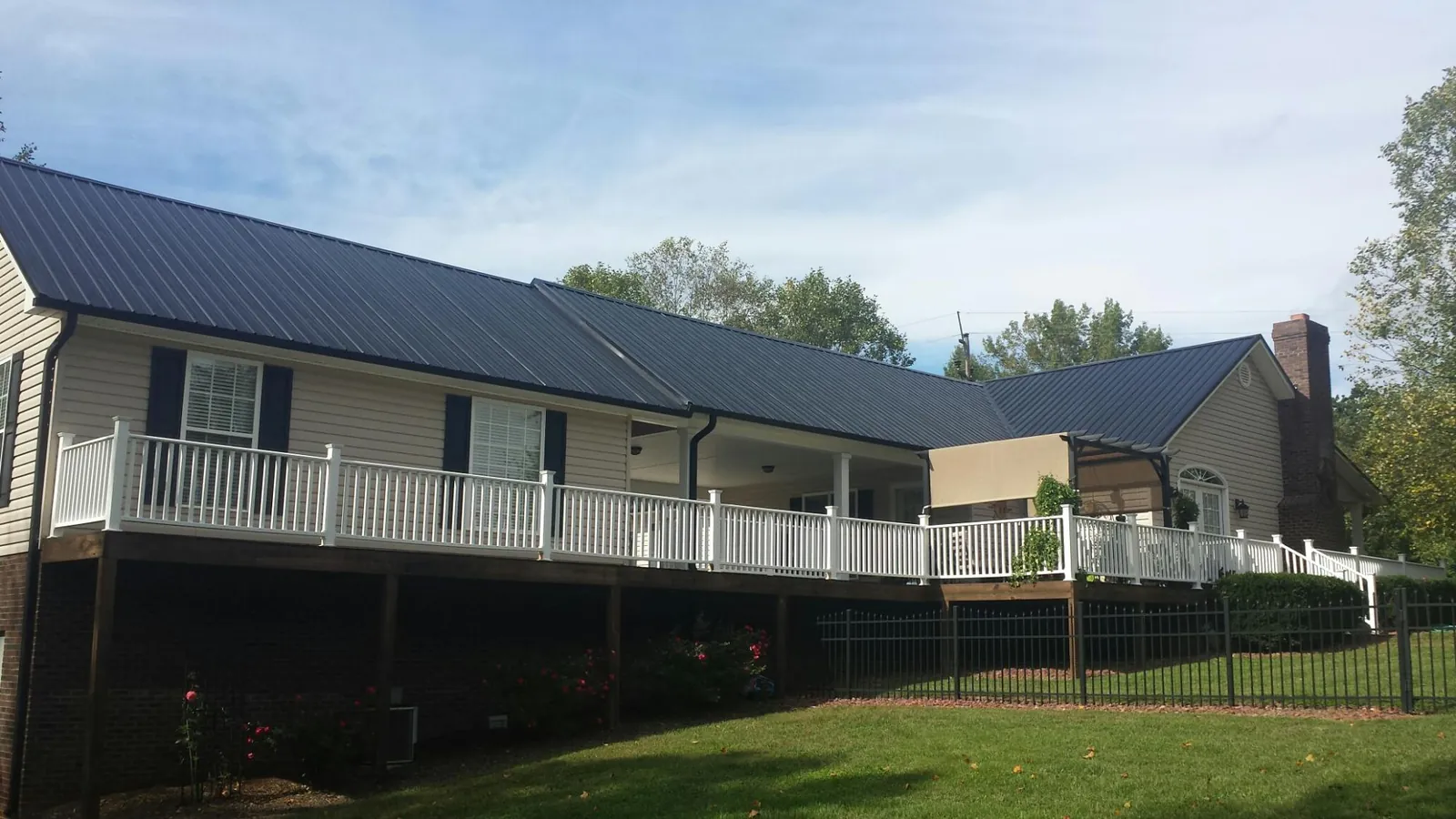 Black metal roof above a long white railed deck on a hillside home in Portage Des Sioux