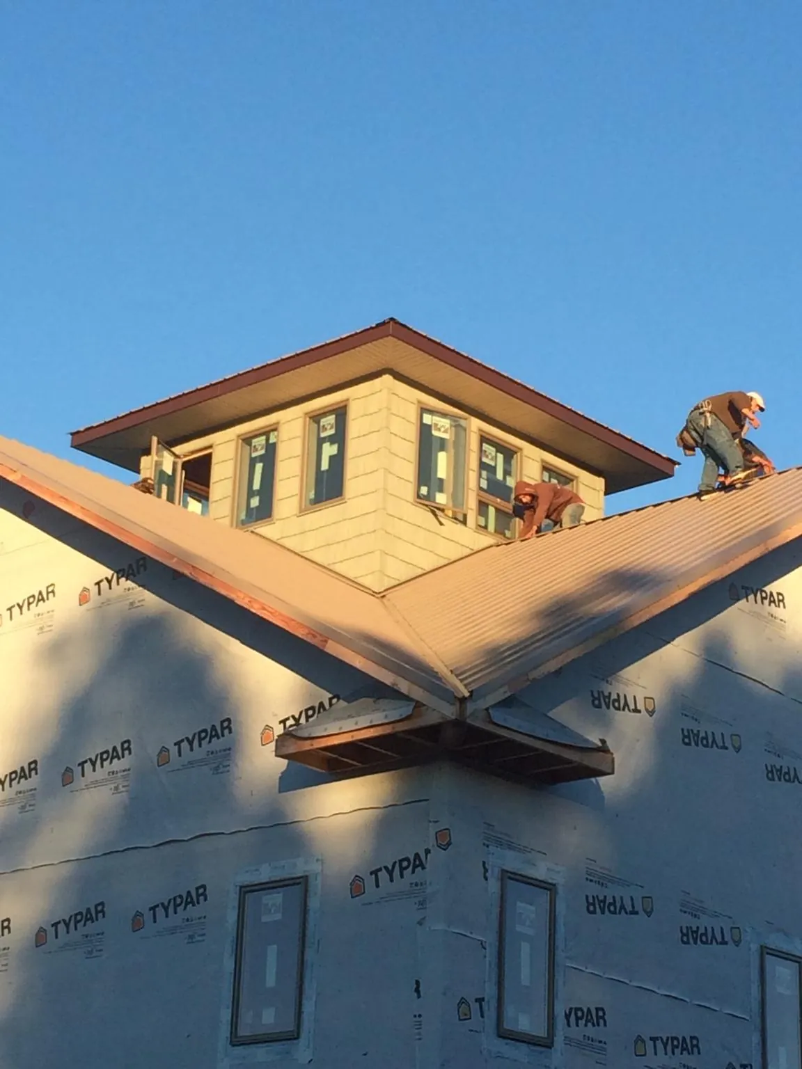Roofers working around a rooftop cupola on a new metal roof at sunset — Roof Waterproofing in Portage Des Sioux by Roofing Brothers